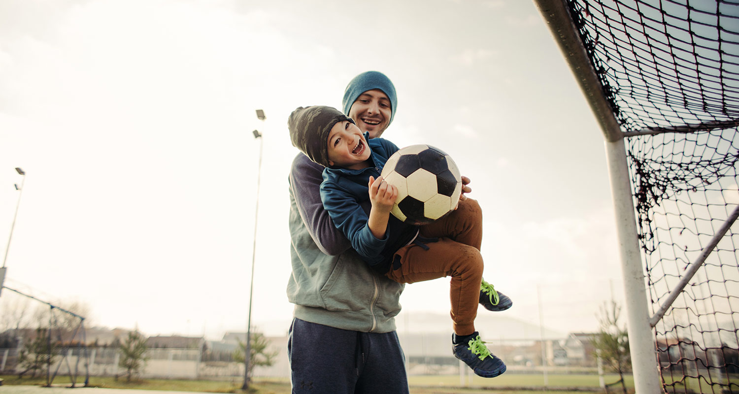 adult and child playing soccer